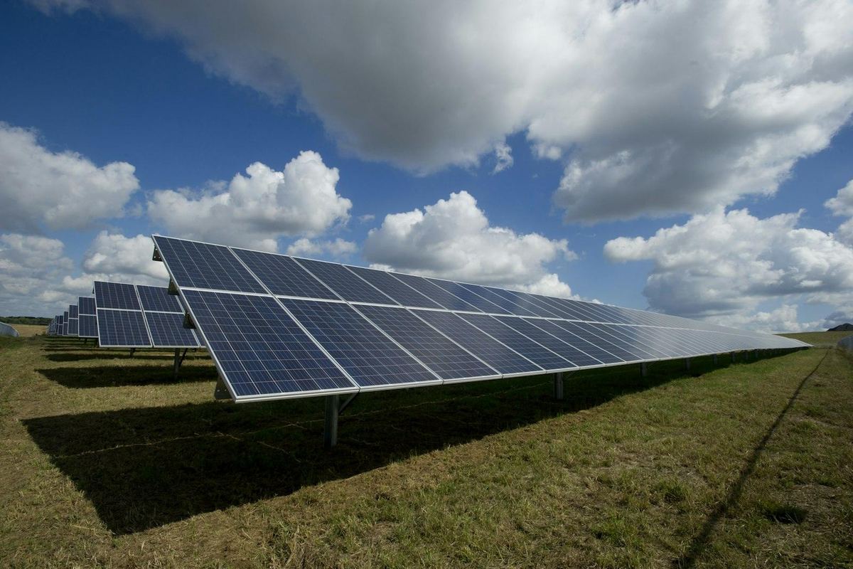 Rijen zonnepanelen onder een blauwe lucht